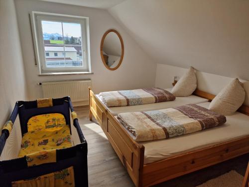 a bedroom with two beds and a mirror and a window at Ferienwohnung Ingrid in Kressbronn am Bodensee