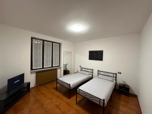 Cette chambre comprend 2 lits et une télévision à écran plat. dans l'établissement The Grace Place Oleggio, à Oleggio