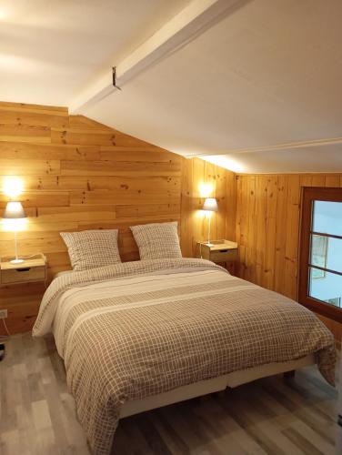 - une chambre avec un grand lit et des murs en bois dans l'établissement Le gîte du Galou, à Sully