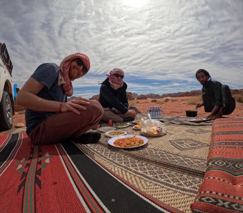 a group of people sitting on a table with food at Bedouin oasis in Wadi Rum