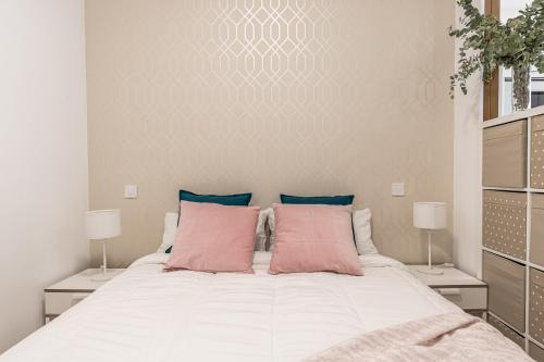 BNBHolder Hunky ATOCHA في مدريد: غرفة نوم مع سرير أبيض كبير مع وسائد وردية