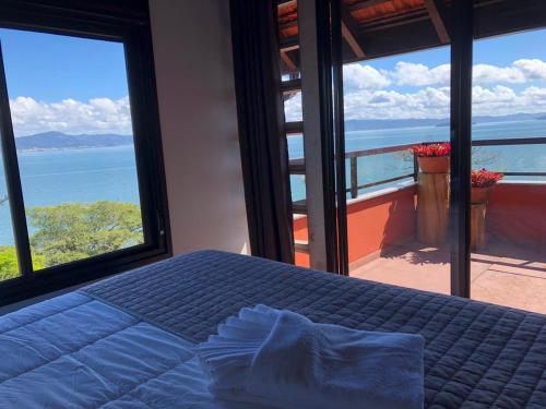 a bedroom with a bed with a view of the ocean at Refúgio do Cacupé in Florianópolis