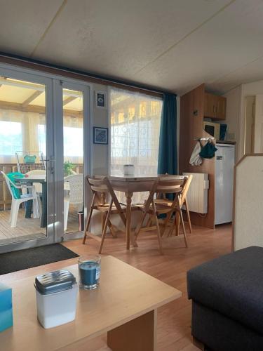 un salon avec une table et une cuisine dans l'établissement mobil loc a la semaine, à Portbail