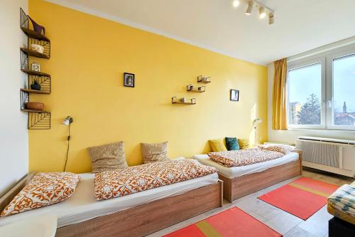 two beds in a room with a yellow wall at Market Apartman Sopron in Sopron