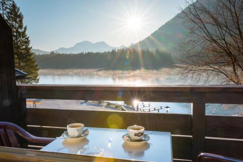 two cups of coffee on a table with a view of a lake at Gasthaus-Pension Seeklause in Ramsau