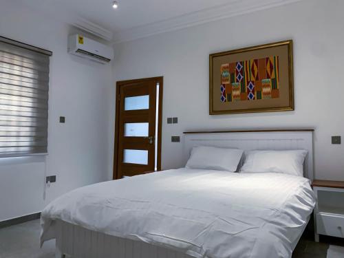 - une chambre dotée d'un lit blanc avec une photo sur le mur dans l'établissement Cony’s Guest House, à Kwabenyan