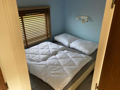 1 cama con sábanas blancas y almohadas en una habitación en Tiny house CC4 - it Soal Workum, en Workum