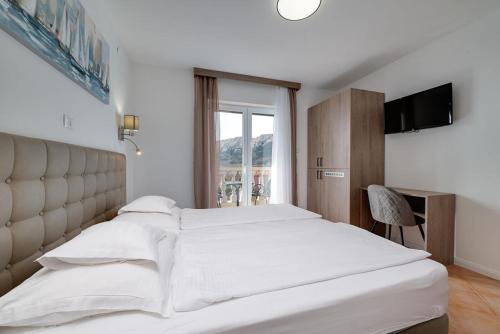 - une chambre avec un grand lit blanc et une fenêtre dans l'établissement Bed & Breakfast Došen, à Baška