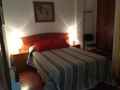 a bedroom with a bed with two red pillows at LOFT AL LADO DE LA PLAYA Y EL MAR in Porto de Espasante