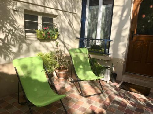 Deux chaises vertes assises devant une maison dans l'établissement Belle chambre avec cuisine et salle de bain à la porte de Paris, à Ivry-sur-Seine