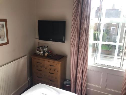 a bedroom with a television and a dresser with a window at The Apple House in York