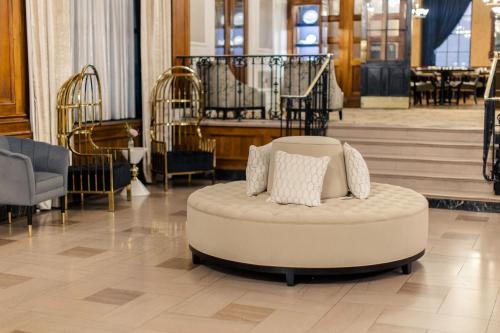 a white couch in a lobby with stairs and tables at The Lord Nelson Hotel & Suites in Halifax