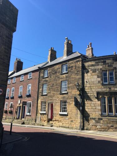 an old brick building with a red door on a street at Lionsgate View - luxury apartment opposite Alnwick Castle in Alnwick