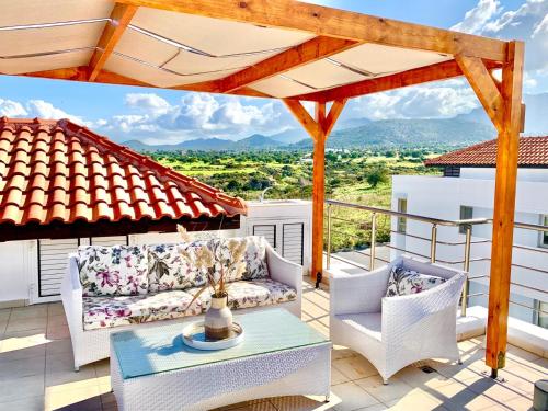 a patio with a couch and chairs on a balcony at Boho Bay Apartment in Akanthou