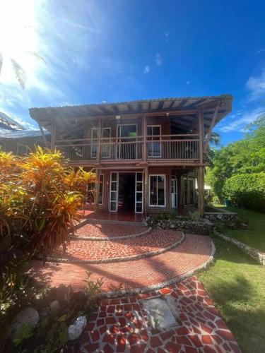 une grande maison avec une terrasse couverte et une passerelle dans l'établissement Island-style lodging & beach club, à Tierra Bomba