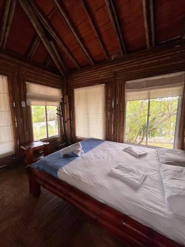 Cette chambre en bois comprend un grand lit et 2 fenêtres. dans l'établissement Island-style lodging & beach club, à Tierra Bomba