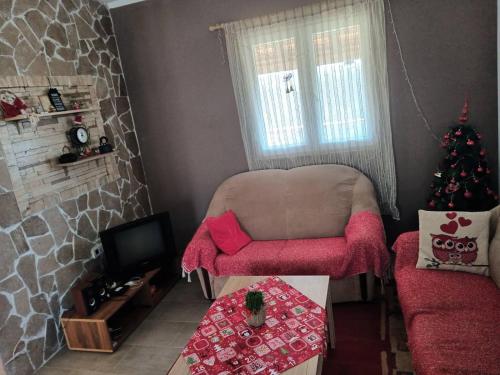 een woonkamer met een kerstboom en een stoel bij Bandici house in Podgorica