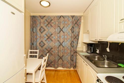 eine Küche mit einem Waschbecken, einem Tisch und einem Vorhang in der Unterkunft 2-Bedroom Apartment in Heart of City Center in Turku