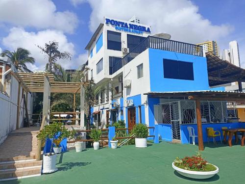 um edifício azul e branco com plantas em frente em Ponta Negra Suites & Apart em Natal