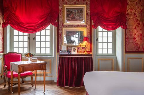 a bedroom with red curtains and a desk and a bed at Relais & Château Louise de La Vallière in Reugny