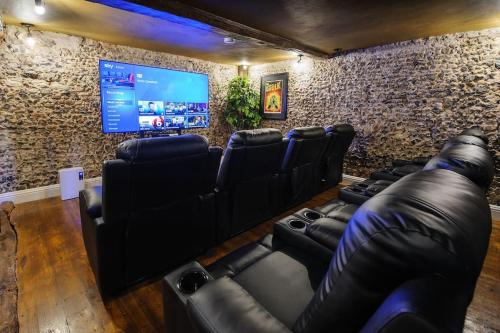 a room with black leather chairs and a flat screen tv at The Famous Harry Potter House, Hot Tub, Cinema Room, Sky TV in Saffron Walden