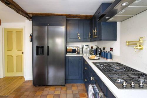 a kitchen with blue cabinets and a stainless steel refrigerator at The Famous Harry Potter House, Hot Tub, Cinema Room, Sky TV in Saffron Walden