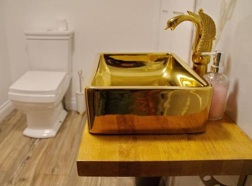 a bathroom with a gold sink and a toilet at The Famous Harry Potter House, Hot Tub, Cinema Room, Sky TV in Saffron Walden