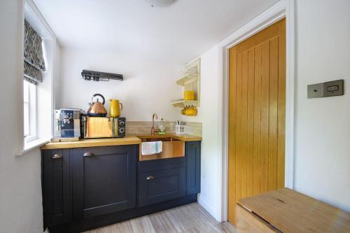 a kitchen with blue cabinets and a wooden door at The Famous Harry Potter House, Hot Tub, Cinema Room, Sky TV in Saffron Walden