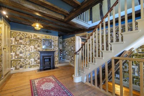 a living room with a staircase and a fireplace at The Famous Harry Potter House, Hot Tub, Cinema Room, Sky TV in Saffron Walden