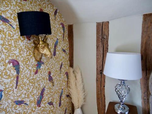 a painting of a head on a wall next to a lamp at The Famous Harry Potter House, Hot Tub, Cinema Room, Sky TV in Saffron Walden
