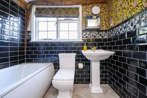 a bathroom with a toilet and a sink and a tub at The Famous Harry Potter House, Hot Tub, Cinema Room, Sky TV in Saffron Walden