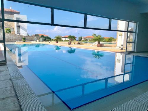 a large swimming pool with blue water in a building at Boho Bay Apartment in Akanthou