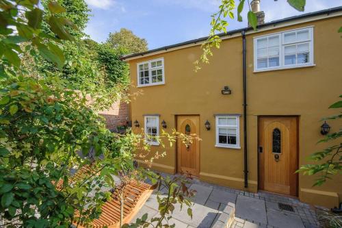 una casa amarilla con dos puertas y un patio en Versace 2 Bed Manor House With Hot Tub, en Saffron Walden