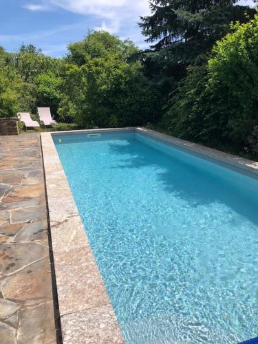une piscine avec de l'eau bleue dans une cour dans l'établissement Maisonnette de charme Les Jardins de Lou, à Boussac