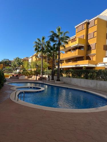 a swimming pool in front of a building with palm trees at Apartamento Punta Prima in Torrevieja