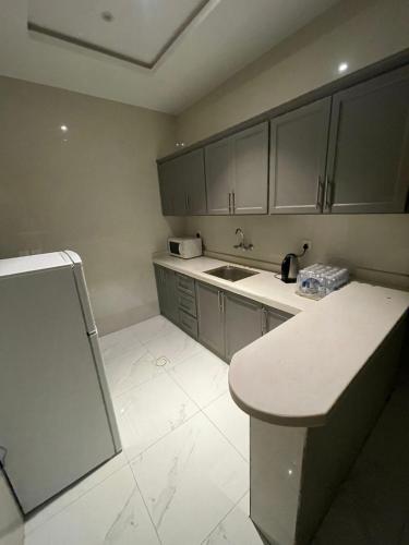 uma cozinha com armários cinzentos, um lavatório e um balcão em الجود مخيم شقة استراحة بيت em Khamis Mushayt