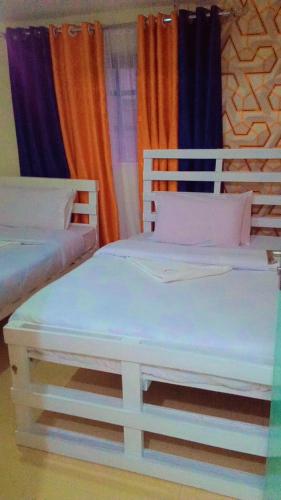 two white beds in a room with curtains at NIKIFLATS in Nakuru