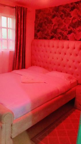 Una cama roja en una habitación con una pared roja. en NIKIFLATS en Nakuru