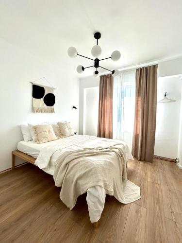 ブカレストにあるUrban Parkside Retreat Cozy 2-Bed Ap by Metroの白いベッドルーム(大型ベッド1台、シャンデリア付)
