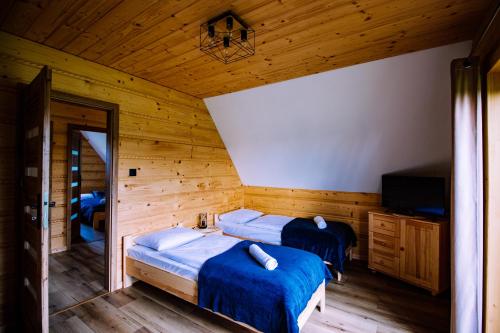 two beds in a room with wooden walls at Sielanka u Stanka in Szaflary