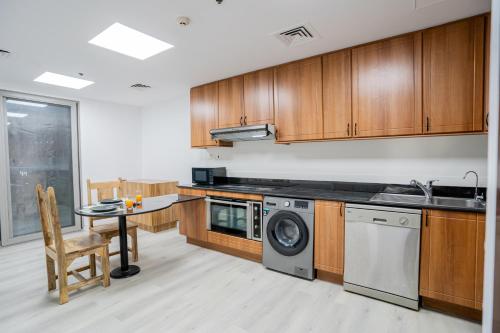 a kitchen with wooden cabinets and a washing machine at Vibes by Beds and Company - Room in Dubai