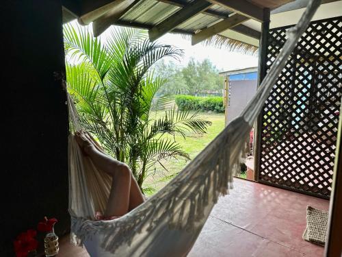 a woman sitting in a hammock on a porch at PARAÍSO Sunset Bungalows in Hanga Roa