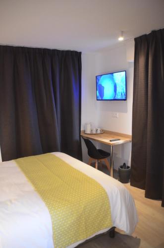 a bedroom with a bed and a desk and a television at Forgeron de seclin in Seclin