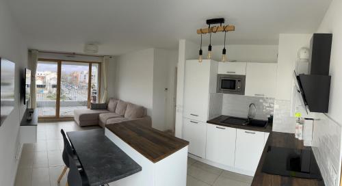 cocina y sala de estar con armarios blancos y sofá en 3 pièces à 4min du RER B, en Saint-Denis