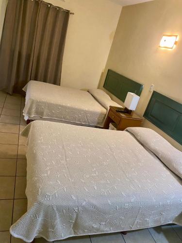 a hotel room with two beds and a table with a lamp at HOTEL POSEIDON SUITES in Los Mochis