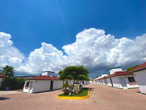 a row of white buildings with a tree in the middle at HOTEL POSEIDON SUITES in Los Mochis