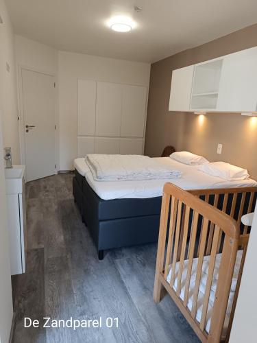 a small bedroom with a bed and a wooden crib at De Zandparel in De Panne