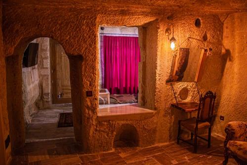 a stone room with a window with a pink curtain at Junior Ottoman Cave in Ürgüp
