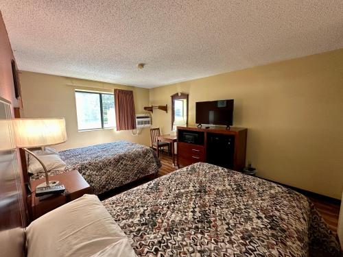 a hotel room with two beds and a television at American Inn-Alexander City in Alexander City