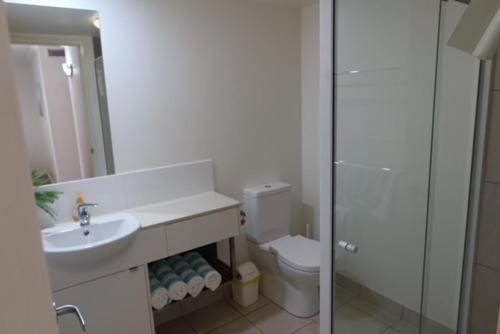 a white bathroom with a sink and a toilet at Ground Floor Luxury Oceanfront Apartment in Bargara